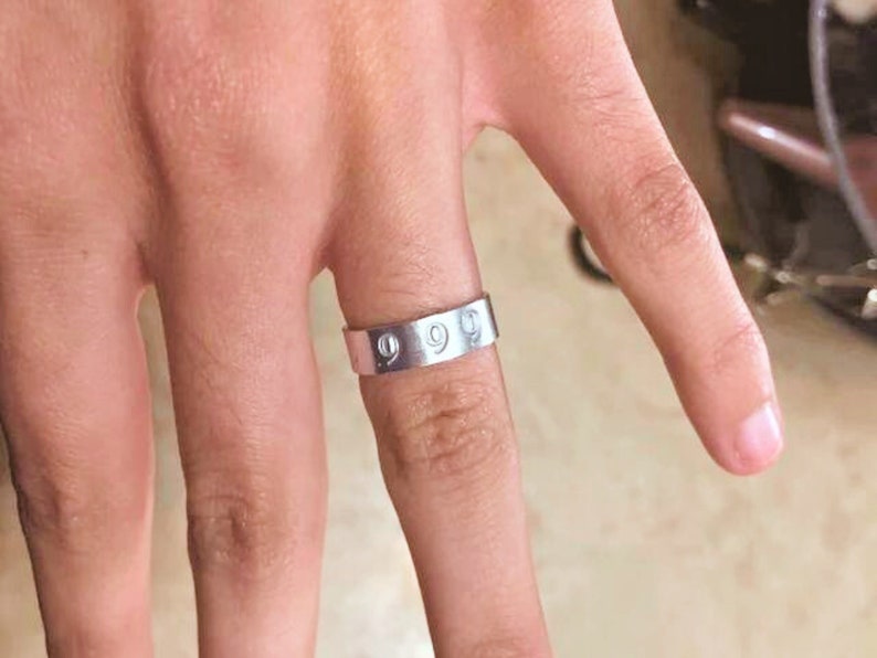 May include: A silver band ring with the number "999" engraved on it.
