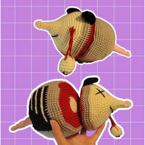 Könnte beinhalten: Ein gehäkeltes Opossum-Spielzeug mit einem rot-schwarz gestreiften Körper. Das Spielzeug ist in zwei Hälften geteilt, wobei eine Hälfte das Innere des Opossums zeigt. Das Spielzeug ist aus Garn gefertigt und hat ein süßes, cartoonartiges Aussehen.