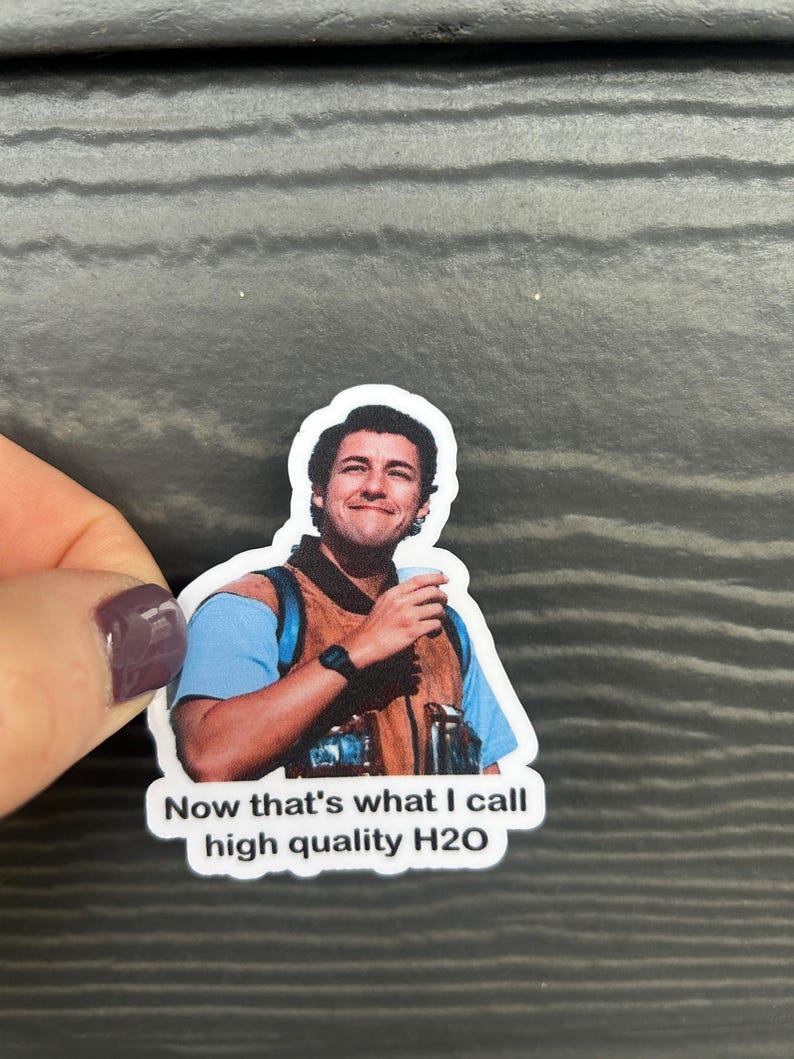 K&ouml;nnte beinhalten: Wei&szlig;er Aufkleber mit einem l&auml;chelnden Mann, der eine Tasse h&auml;lt. Der Mann tr&auml;gt ein blaues Hemd und eine braune Weste. Der Aufkleber tr&auml;gt den Text "Now that's what I call high quality H2O".