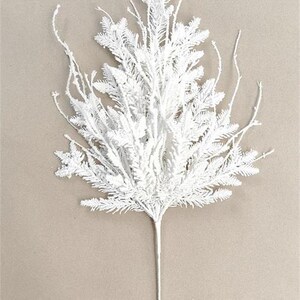 May include: A white artificial evergreen branch with a long stem. The branch is 29 inches tall and 14 inches wide. The text "SQ24-11822" and "14*3*29"H" are printed at the bottom. This decorative piece is suitable for holiday arrangements.
