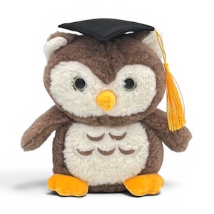 May include: A plush owl toy with brown and white fur, wearing a black graduation cap with a gold tassel. The owl has large, round eyes and orange feet. A cute graduation gift.