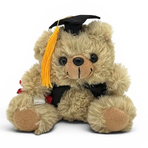 May include: A plush teddy bear in a graduation cap and gown. The bear is light brown with a black cap, a yellow tassel, and a black ribbon. It holds a small scroll, celebrating academic achievement.