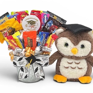 May include: A graduation gift basket with assorted candy and a plush owl wearing a graduation cap. The candy is arranged in a decorative bucket with a graduation-themed ribbon. A round sticker says "Congratulations Graduate".