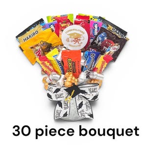 May include: A candy bouquet with a graduation theme. The bouquet includes various candy bars and treats, a graduation cap, and a "Congratulations Graduate" button. The base is wrapped with ribbons that say "Congrats Grad".