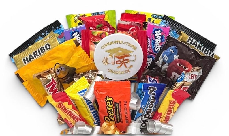 May include: A graduation-themed gift basket filled with assorted candies, including Haribo, Twix, Starburst, Reese's, and Nerds. A white button with gold text that reads "Congratulations Graduate" is in the center.