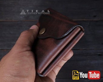 May include: A brown leather wallet with a brass button closure. The wallet is folded in half and has a distressed look. The wallet is being held in a hand.