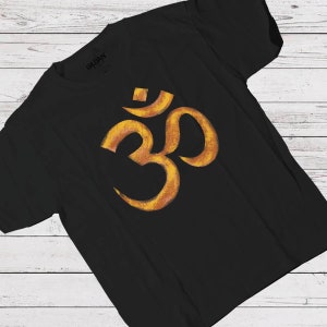 May include: A black t-shirt featuring a gold Om symbol printed on the front. The symbol is a Sanskrit word representing the universe and the sound of creation.
