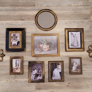 May include: A wall gallery of framed artwork and mirrors. The gallery includes a round mirror with a gold frame, a square mirror with a gold frame, a square mirror with a black frame, a square mirror with a gold frame, a square mirror with a gold frame, a square mirror with a gold frame, a square mirror with a gold frame, a square mirror with a gold frame, and a square mirror with a gold frame. The artwork includes a floral print, a portrait, and a landscape. The gallery is arranged in a symmetrical pattern, with the round mirror in the center.