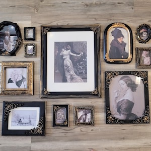 May include: A collection of framed vintage art prints in various sizes and shapes. The frames are black and gold, with ornate detailing. The prints feature portraits and scenes in black and white.