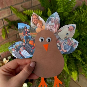 Puede incluir: Una manualidad de pavo hecha de papel marrón con ojos móviles y un pico y patas de papel naranja. Las plumas de la cola están hechas de varios recortes en forma de hoja, cada uno con una fotografía en color diferente de diversas personas.