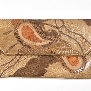 May include: A rectangular shoulder bag with a flap closure, crafted from a patchwork of reptile skin in shades of brown, tan, and orange. The bag features a long, thin strap and a gold-toned clasp.