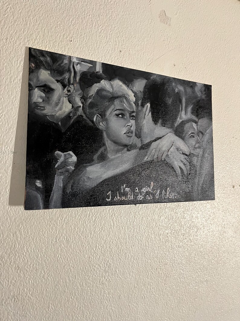 Puede incluir: Pintura en blanco y negro de un grupo de personas. La mujer del centro mira directamente al espectador. El texto "I'm a girl I should do as I like" est&aacute; escrito en pintura blanca en la parte inferior de la pintura.