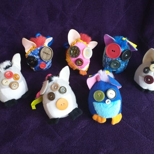 May include: Seven colourful plush toys with button eyes. The toys are made of different fabrics and have various patterns. They are all about the same size and have a similar shape.