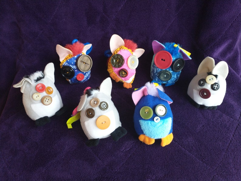 May include: Seven colourful plush toys with button eyes. The toys are made of different fabrics and have various patterns. They are all about the same size and have a similar shape.