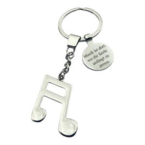 Pode incluir: Chaveiro de nota musical prateada com uma etiqueta redonda que diz "Musik ist dort, wo die Seele anfängt zu atmen."