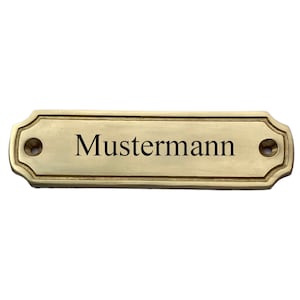 Op de afbeelding: Een messing naamplaatje met afgeronde randen en twee schroefgaten. Het naamplaatje heeft de tekst "Mustermann" gegraveerd in zwart.