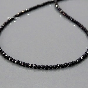 May include: A black beaded necklace made of small, faceted gemstones. The necklace is approximately 18 inches long.