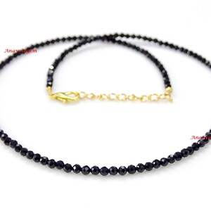 May include: A delicate black spinel gemstone necklace with a gold clasp. The necklace is made of small, round beads and is approximately 18 inches long.