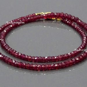 May include: A double strand necklace made of small, faceted, red ruby beads. The necklace is approximately 18 inches long and has a gold clasp.