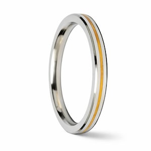Puede incluir: Un anillo plateado con una fina franja dorada en el centro. El anillo es liso y pulido, con un diseño sencillo y elegante. El anillo es probablemente de metal y es adecuado para el uso diario.
