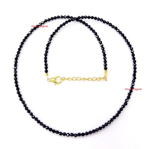 May include: A black gemstone necklace with a gold clasp. The necklace is made of small, round beads and is approximately 18 inches long.