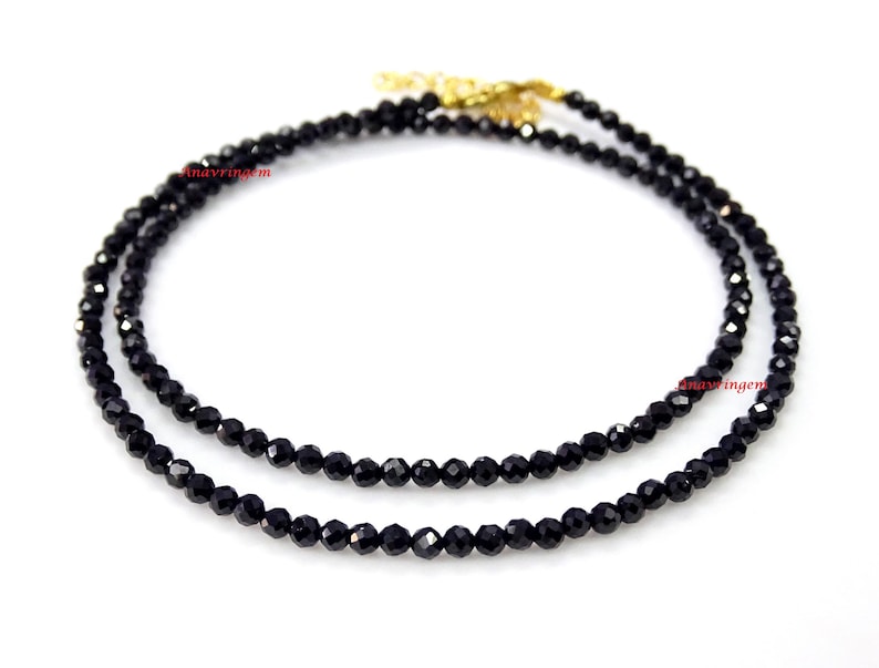 May include: A black spinel gemstone necklace with a gold clasp. The necklace is made of small, faceted beads and is approximately 18 inches long.
