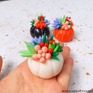 Puede incluir: Tres calabazas en miniatura decoradas con flores de arcilla polimérica de colores. Las calabazas son blancas, negras y naranjas. Las flores son rosas, rojas, azules y verdes.