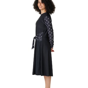 May include: A black long-sleeved dress with white polka dots on the sleeves. The dress has a tie at the waist and a flowing skirt.