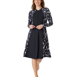 May include: A black and white patterned long-sleeved dress with a zipper at the neck. The dress has a flared skirt and is knee-length.
