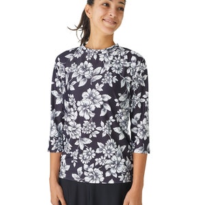 May include: A black and white floral print shirt with three-quarter sleeves. The shirt has a round neckline and a relaxed fit.