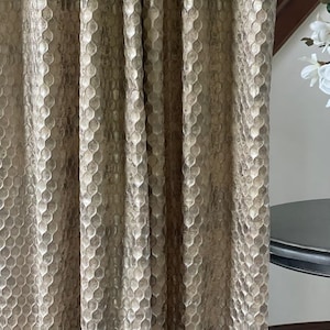 May include: Close-up of a pair of gold curtains with a textured honeycomb pattern.