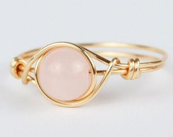 May include: A delicate gold wire ring with a pale pink gemstone. The ring is simple and elegant, perfect for everyday wear.