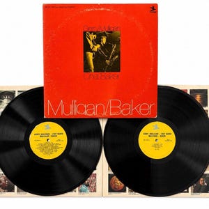 Peut inclure: Un ensemble de disques vinyles avec une pochette orange vif portant le texte Mulligan/Baker et Gerry Mulligan Chet Baker. La pochette présente une photographie en noir et blanc de musiciens. Deux disques vinyles noirs avec des étiquettes jaunes sont inclus.