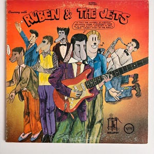 May include: A white ceramic mug with a black handle and the text "But First, Coffee" in a black, bold font. The mug is on a white surface.