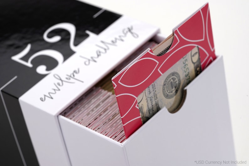 以下が含まれることがあります： 前面に「52 envelope challenge」という文字が印刷された白い箱。箱が開いており、白地に幾何学模様が描かれた赤い封筒が引き出されている。封筒には窓があり、米ドル紙幣が見えている。