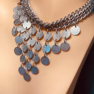 May include: A white ceramic mug with a black handle and the text "But First, Coffee" in a bold, black font. The mug is sitting on a wooden surface. The mug is approximately 4 inches tall.