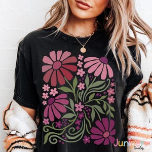 May include: Black t-shirt featuring a floral design with large pink and burgundy flowers, smaller pink flowers, and green leaves. The text "Jumper Smiles" is visible in the lower right corner. The shirt has a vintage, worn look.