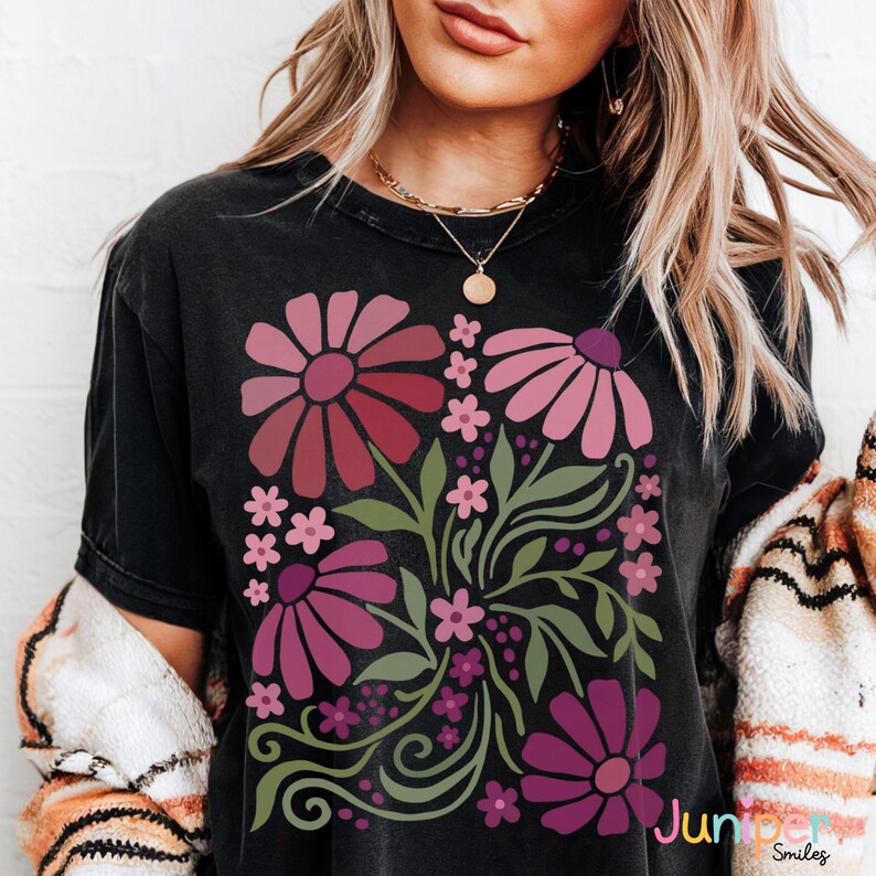 May include: Black t-shirt featuring a floral design with large pink and burgundy flowers, smaller pink flowers, and green leaves. The text "Jumper Smiles" is visible in the lower right corner. The shirt has a vintage, worn look.