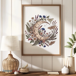 May include: A framed art print featuring a crescent moon design with floral and butterfly accents. The artwork includes daisies, ferns, and berries, with a warm color palette. The frame is a light brown color.