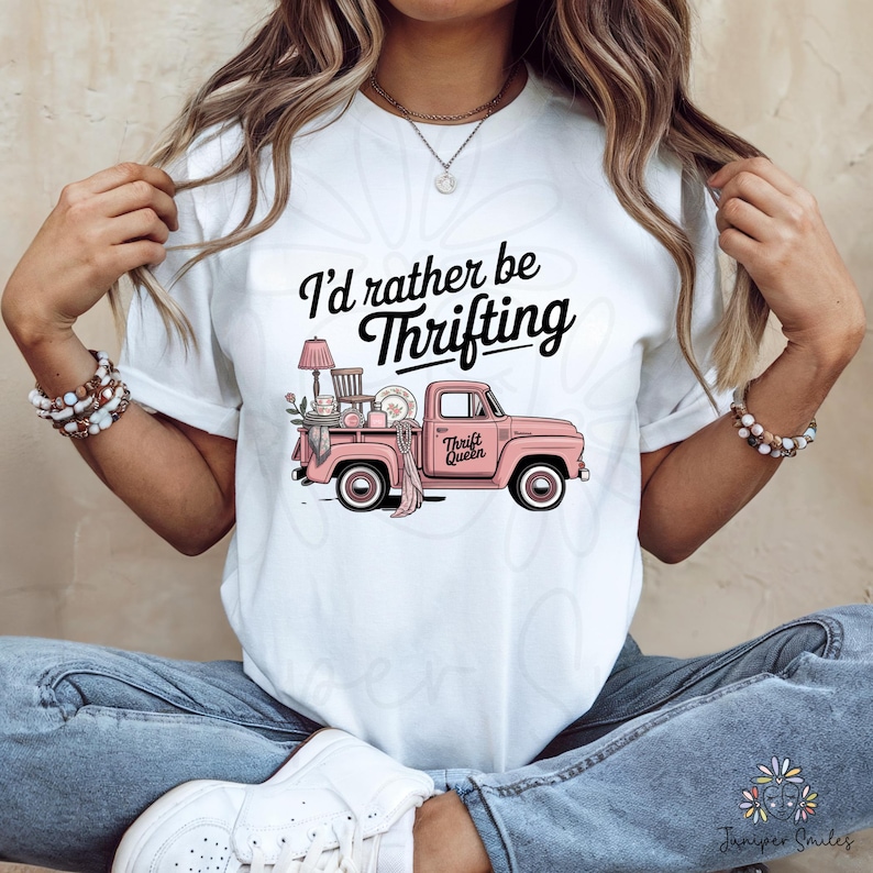 May include: White t-shirt featuring the text "I'd rather be Thrifting" in black script. A pink vintage truck graphic is filled with thrifted items. The truck has the words "Thrift Queen" on the side.