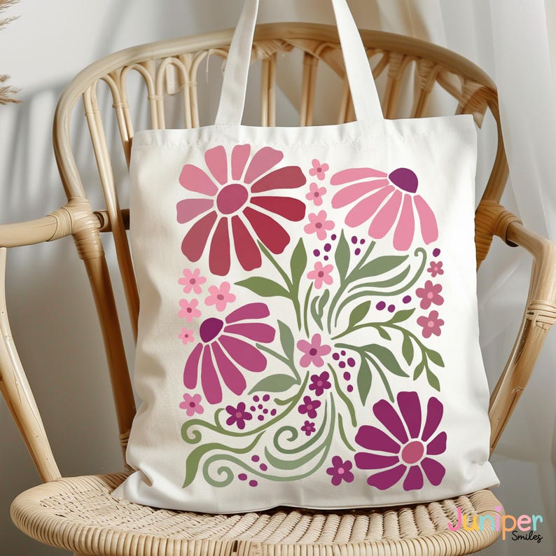 May include: A white tote bag featuring a floral design in shades of pink, red, and green. The flowers are stylized and arranged with green leaves and small pink blossoms. The bag has two white handles.