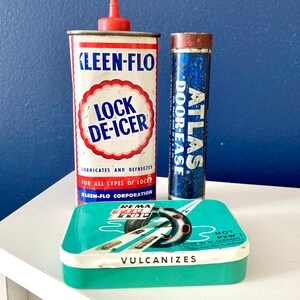 Peut inclure: Trois boîtes en métal vintage. La première boîte est rouge, blanche et bleue et indique "Kleen-Flo Lock De-Icer" et "Lubrifie et dégivre tous types de serrures". La deuxième boîte est bleue et indique "Atlas Door-Ease". La troisième boîte est turquoise et indique "Rema Top Vulcanizes" et "Fabriqué en Allemagne de l'Ouest".