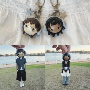 May include: Two handmade keychains featuring miniature doll figures with headphones. One doll has brown hair and glasses, the other has black hair. Each keychain has a silver clasp and a star charm. The dolls are also shown in full body form.