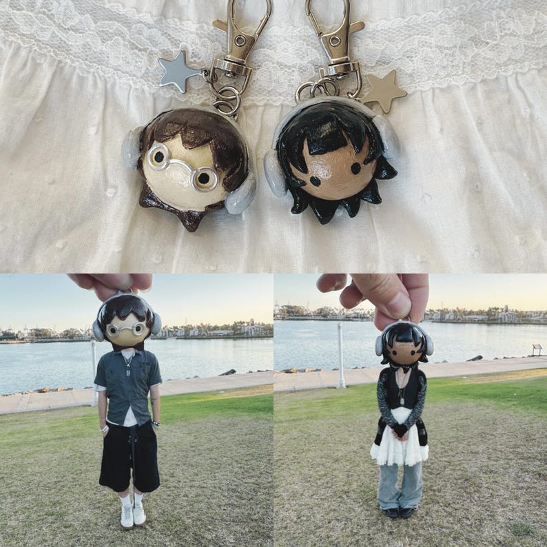 May include: Two handmade keychains featuring miniature doll figures with headphones. One doll has brown hair and glasses, the other has black hair. Each keychain has a silver clasp and a star charm. The dolls are also shown in full body form.