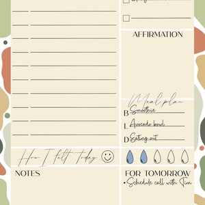May include: A beige daily planner with a light brown, green, and orange abstract background. The planner has sections for goals, affirmations, meal plans, and notes. The planner also includes a section for "How I felt today" with a smiley face and water drop icons. The date is 21.04.21.