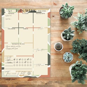 May include: A weekly planner with a colourful abstract design. The planner includes sections for Monday through Friday, weekend plans, health, sport, meditation, and inspiration. The planner also includes a section for "This week I felt" with a smiley face.