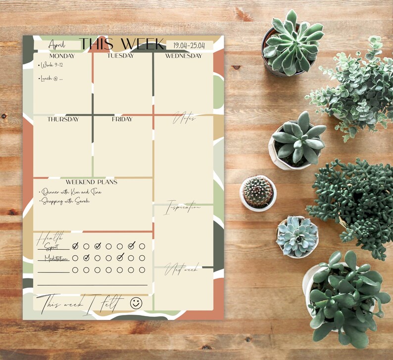 May include: A weekly planner with a colourful abstract design. The planner includes sections for Monday through Friday, weekend plans, health, sport, meditation, and inspiration. The planner also includes a section for "This week I felt" with a smiley face.