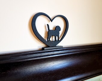 May include: Black metal heart-shaped silhouette with a dog silhouette inside. The heart is mounted on a dark wood frame.