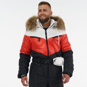 Puede incluir: Un mono de nieve de invierno en negro, rojo y blanco. La chaqueta tiene una capucha con ribete de piel y un panel blanco en el pecho. Los pantalones son negros con detalles en rojo y blanco. Se lleva una riñonera blanca en la cintura.