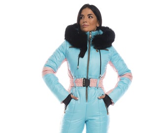 May include: A light blue ski suit with a pink stripe down the side and a black fur-trimmed hood. The suit has a belt with a gold buckle.